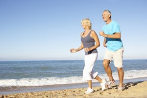 Older Couple Running Along Beach